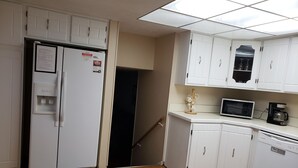 A kitchen with white cabinets, a microwave, a coffee maker, and a refrigerator. - Spacious SW Omaha Home Near I-80, Garage Game Room, Family-Friendly, Safe Area! (Omaha)