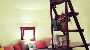 A living room with a sofa, a coffee table with plates and a candle, and a bookshelf with books and a globe. - Immaculate 2-Bed Cottage near Krka Waterfalls (Rupe)