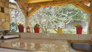 A kitchen with a tiled countertop, a sink, and a window with potted plants. - Immaculate 2-Bed Cottage near Krka Waterfalls (Rupe)