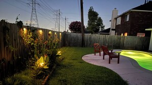 A backyard with a wooden fence, a small pool with green lighting, and a wooden chair. - 4110 David & Jennie’s Place (Missouri City)