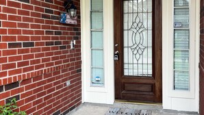 A brick house with a wooden front door, a welcome mat, and a mailbox. - 4110 David & Jennie’s Place (Missouri City)