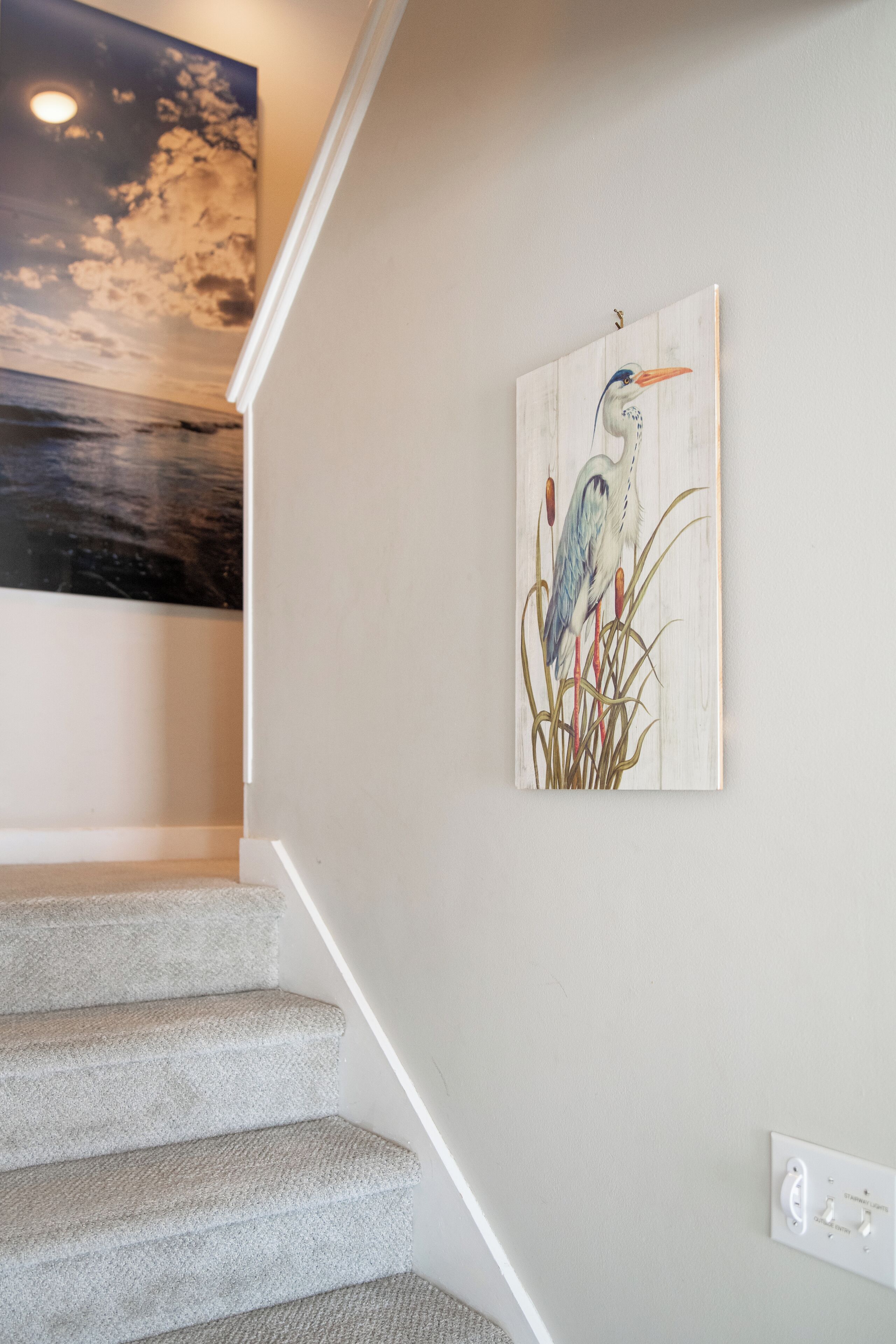 Una escala amb una obra d'art penjada a la paret que representa un flamenc.