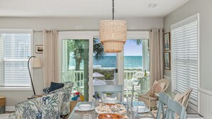 A dining area with a view of the ocean, a wicker hanging light fixture, and a table set for a meal. - Portofino I 1424 - Oceanfront in Garden City Beach (Garden City Beach)