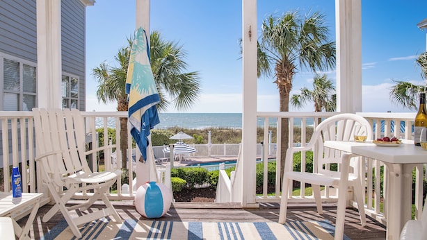 A covered outdoor area with white furniture, a pool, and a view of the ocean. - Portofino I 1424 - Oceanfront in Garden City Beach (Garden City Beach)