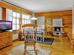 Ein gemütliches Wohnzimmer mit Holzstuhl, Fernseher und Kamin.