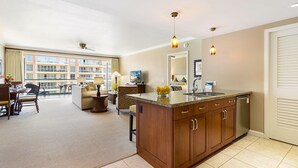 A hotel room with a large window, a balcony, a dining area, and a kitchen.