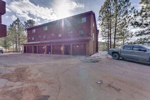 A multi-story building with a garage and a truck parked in front. - Walk to Lifts: Ski-In/Ski-Out Angel Fire Condo (Angel Fire)