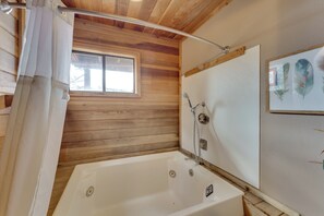 A wooden-paneled bathroom with a bathtub, a window, and a shower. - Walk to Lifts: Ski-In/Ski-Out Angel Fire Condo (Angel Fire)