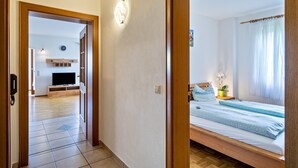 Une chambre à coucher avec un lit, une table de chevet, une télévision et une fenêtre avec des rideaux.