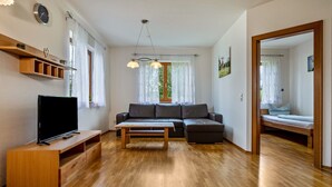 Un salon moderne avec un canapé, un téléviseur, une table basse en bois et un miroir.