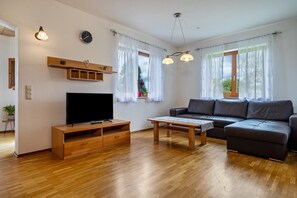 A living room with a TV, sofa, wooden coffee table, and a wooden shelf. - Comfortable vacation apartment 70 m² with private terrace (Gornhofen / Ravensburg)