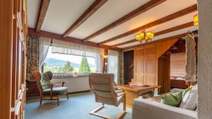 A cozy room with wooden beams, a sofa, two chairs, a table, and a view of the outdoors. - Am Hohen Bogen by Interhome (Arrach)