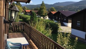 A balcony with a table and chairs, overlooking a village with traditional houses and mountains in the background. - Am Hohen Bogen by Interhome (Arrach)