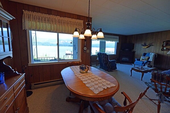 Una sala de estar acogedora con una mesa de comedor de madera, una chimenea y vistas a un lago.