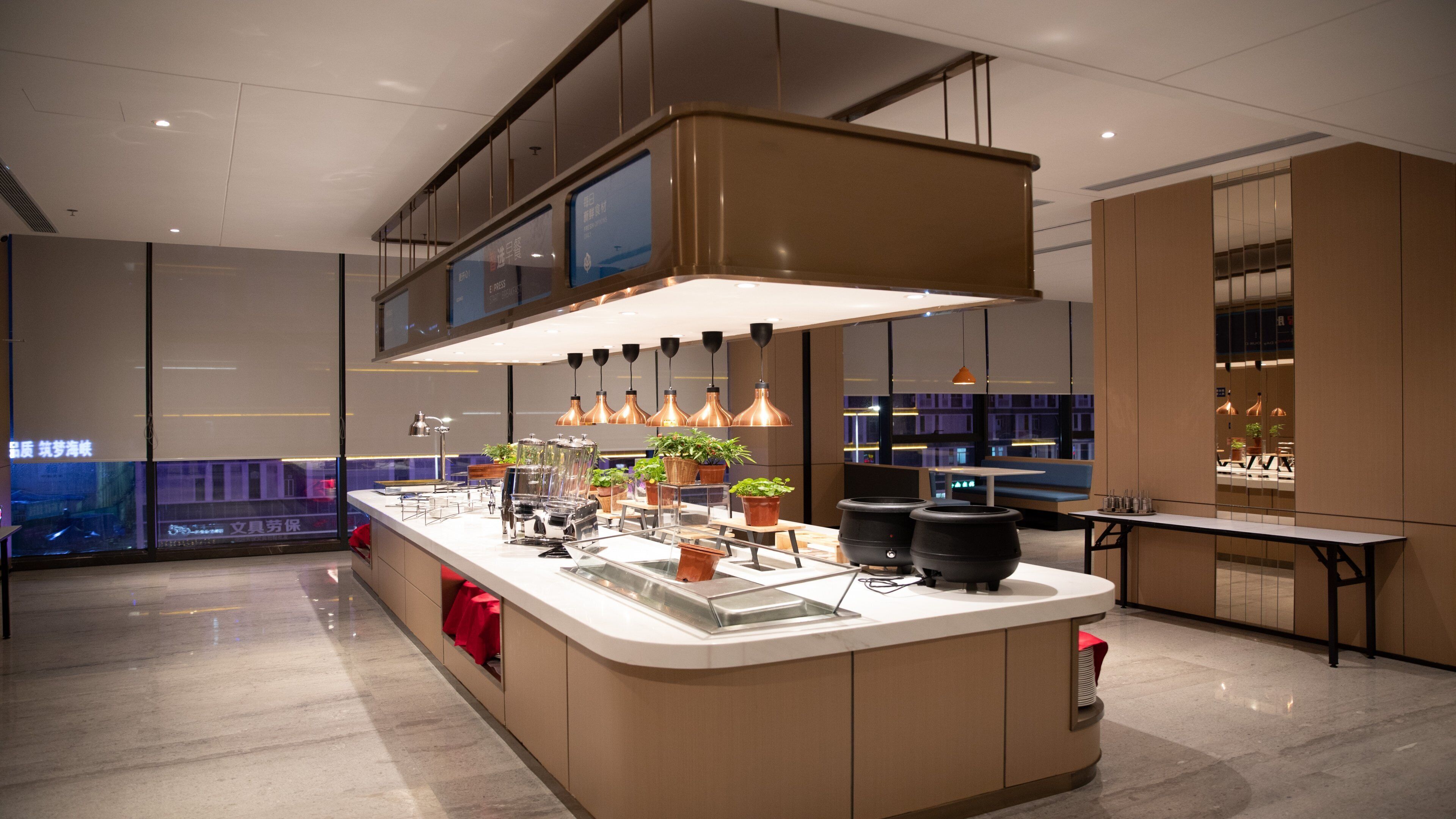 A modern kitchen with a central island, pendant lighting, and potted plants.