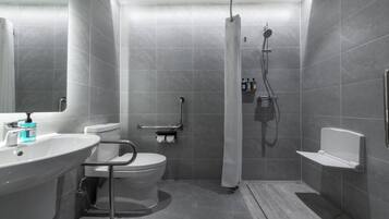 Ein modernes Badezimmer mit Toilette, Waschbecken, Dusche und Haltegriffen.