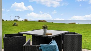 A patio with wicker furniture and a view of the sea. - Charming 2-bedroom 12H Ocean Retreat, Summerhouse (Middelfart)