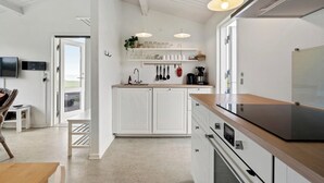 A modern kitchen with white cabinetry, a wooden countertop, and pendant lighting. - Charming 2-bedroom 12H Ocean Retreat, Summerhouse (Middelfart)