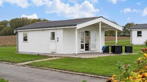 A small, single-story white building with a covered porch and a small outdoor seating area. - Charming 2-bedroom 12H Ocean Retreat, Summerhouse (Middelfart)