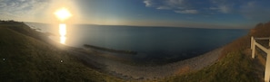 A coastal landscape with a wooden walkway leading to a rocky shore.