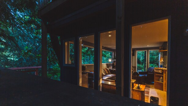 Une maison moderne dotée de grandes portes vitrées qui donnent sur un espace de vie comprenant un canapé et une table.