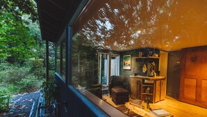 L’intérieur d’un chalet chaleureux, avec une table à manger en bois, un fauteuil confortable et une bibliothèque.