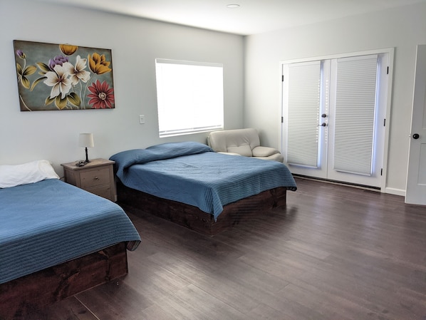 A bedroom with two beds, a window, a door, and a painting on the wall. - Brand New Studio, Confortable, and gated parking, close to downtown. (Ensenada)
