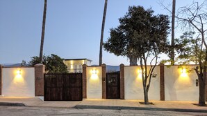 A gated property with a wooden gate, brick walls, and wall-mounted lights. - Brand New Studio, Confortable, and gated parking, close to downtown. (Ensenada)