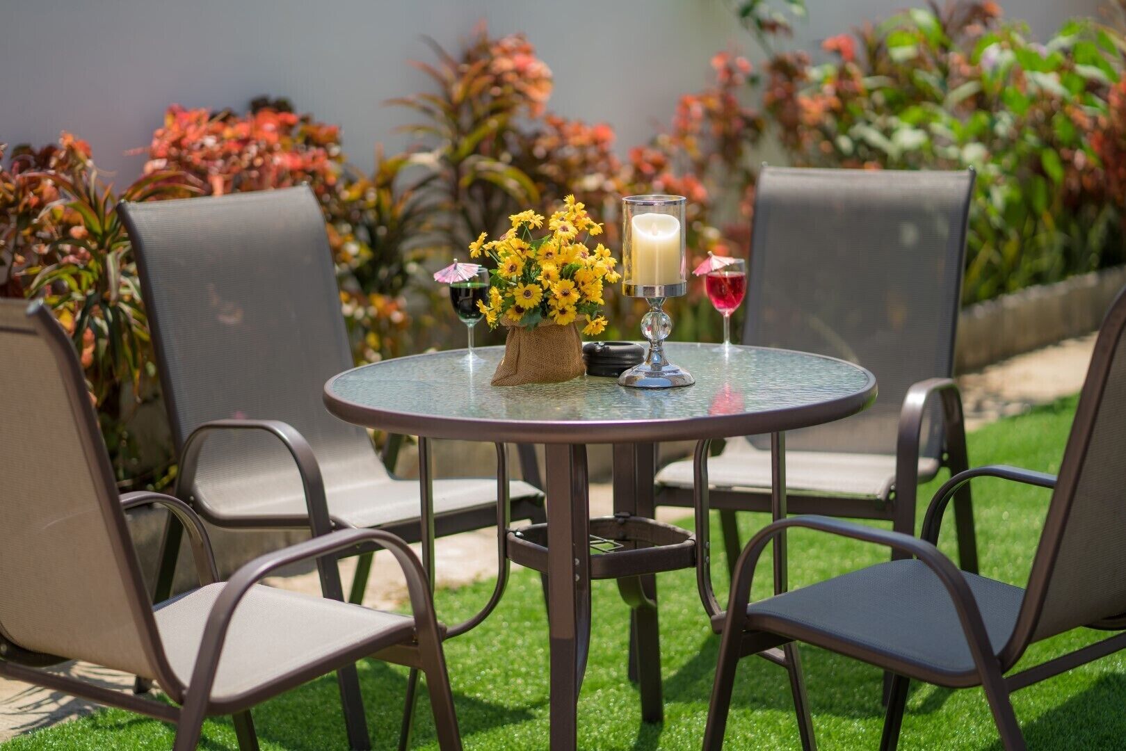 Un área de estar al aire libre con una mesa redonda, sillas y un jarrón con flores amarillas.