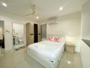 Un dormitorio moderno con una cama grande, ventilador de techo, equipo de aire acondicionado y una mesita de noche con lámpara.