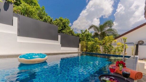 Una piscina azul cristalina con un flotador, una toalla y una bandeja con bebidas y aperitivos.