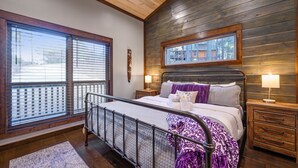 A bedroom with a bed, bedside tables, a window, and a view of the outside. - Glorious Sunset - Hot Tub - Fire Pit - Game Room - Forest Views - Sleeps 8 (BROKEN BOW)