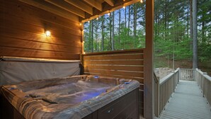 A hot tub with a wooden deck and a view of a forest. - Glorious Sunset - Hot Tub - Fire Pit - Game Room - Forest Views - Sleeps 8 (BROKEN BOW)