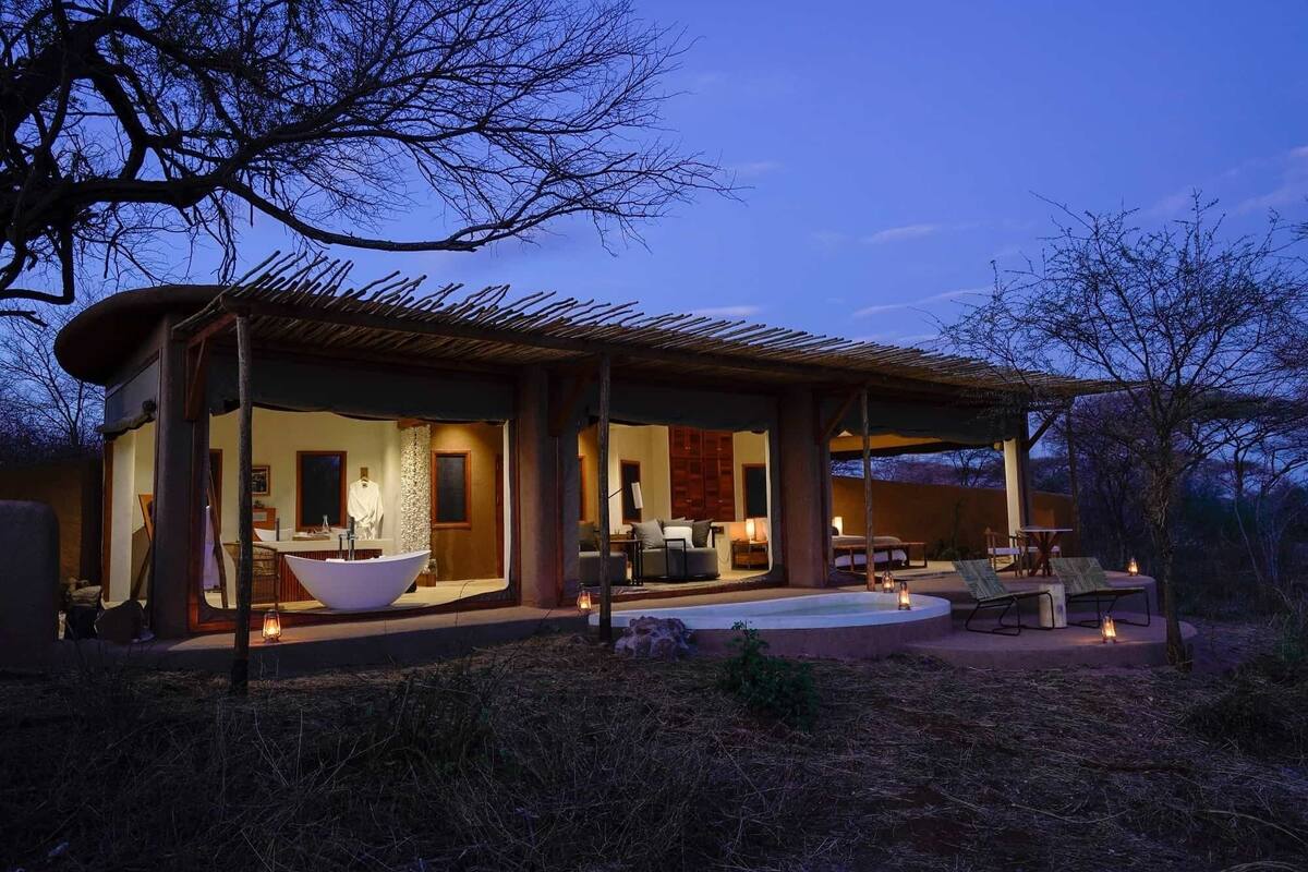 A modern outdoor living space with a large white bathtub, a dining area, and a cozy seating area with a fire pit.