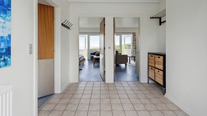 Un couloir menant à un espace de vie avec vue sur l’extérieur, un porte-manteau et un meuble de rangement en forme de panier.