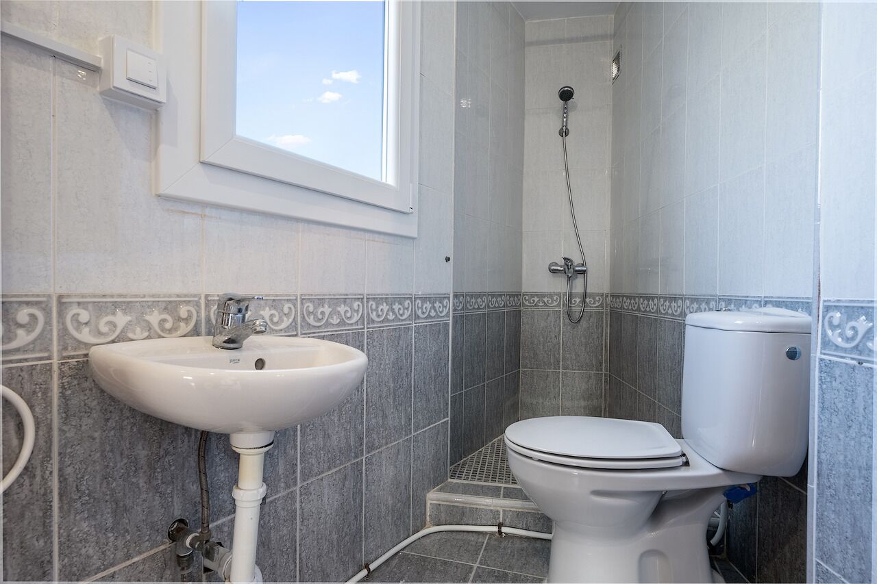 Un baño con lavamanos, inodoro y ducha blancos.
