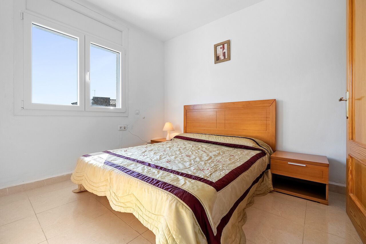A bedroom with a bed, nightstand, and a window.