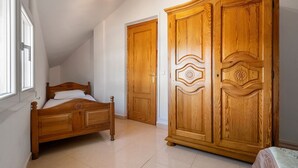 Ein Schlafzimmer mit einem hölzernen Bett, einem Kleiderschrank und einem Fenster.