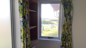 A window with a view of a grassy area and a structure in the distance.
