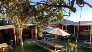 A backyard with a swing set, picnic tables, and a covered seating area.