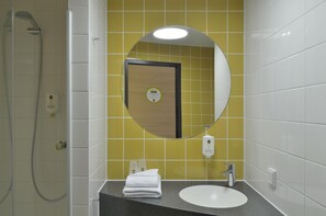 Une salle de bain avec un lavabo blanc, un miroir et une douche.