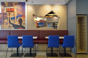 Een modern interieur met een rode bank, blauwe stoelen en een muur met een geometrisch ontwerp en een poster.