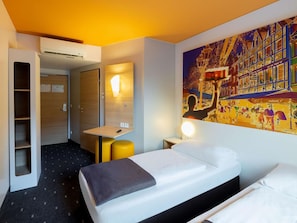 Een hotelkamer met een bed, een bureau, een stoel, een kledingkast en een groot schilderij aan de muur.
