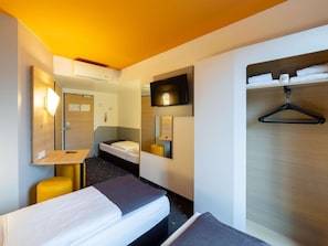 A hotel room with a bed, a desk, a chair, a TV, and a coat rack. - B&B Hotel Düsseldorf-city (Düsseldorf)