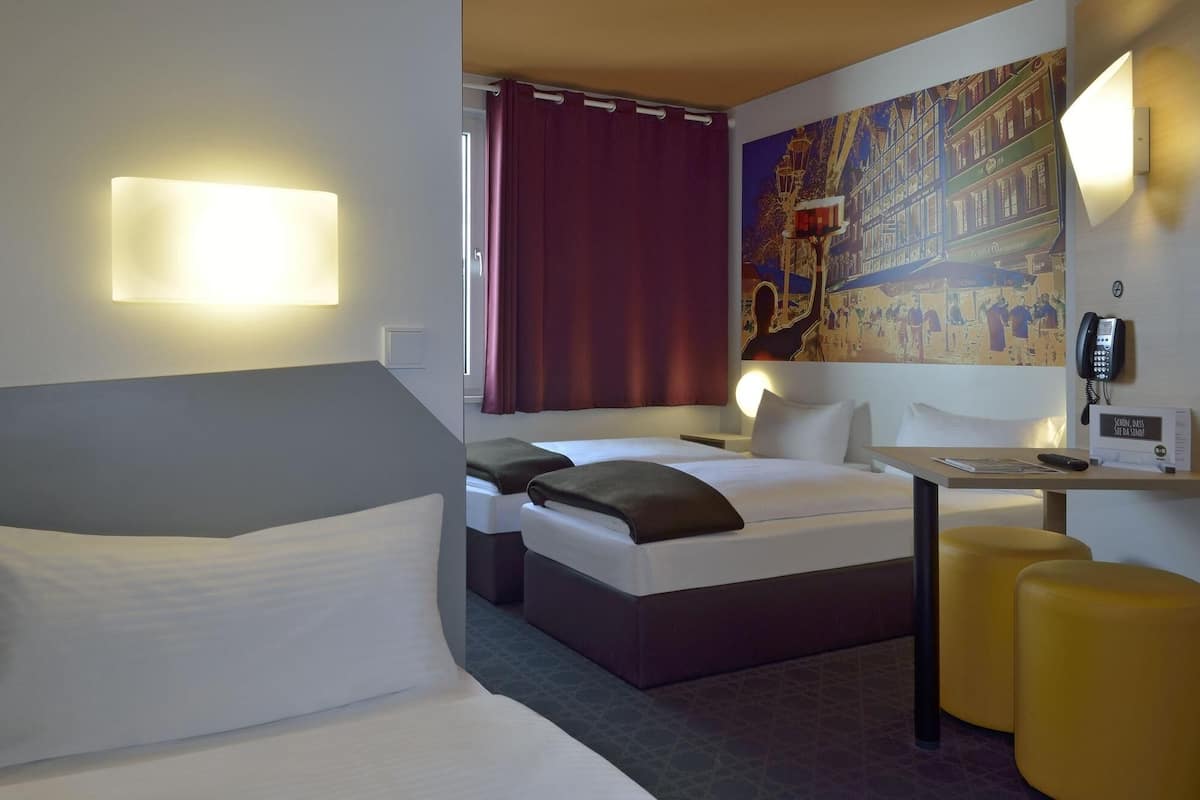 Une chambre d’hôtel avec un lit, un bureau, un téléphone et un tableau au mur.