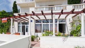 En hvid bygning med en træpergola, plantekasser og et skilt, der viser "Apartments".