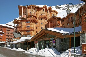 Un bâtiment en bois à plusieurs étages, doté de balcons, d’un magasin de ski et d’une enseigne indiquant « Altitude ».