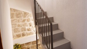 Eine Treppe mit einer Steinmauer an einer Seite und einer schlichten Wand an der anderen, die zu einem Zwischenpodest führt.