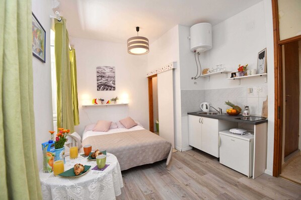Cozy hotel room with a bed, dining area, and kitchenette, perfect for a relaxing stay.