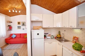 Cozy living space with a kitchenette, featuring a sofa, patterned rug, and modern kitchen amenities.